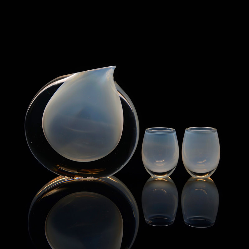 a sculptural opaline modernist glass pitcher set with a black background